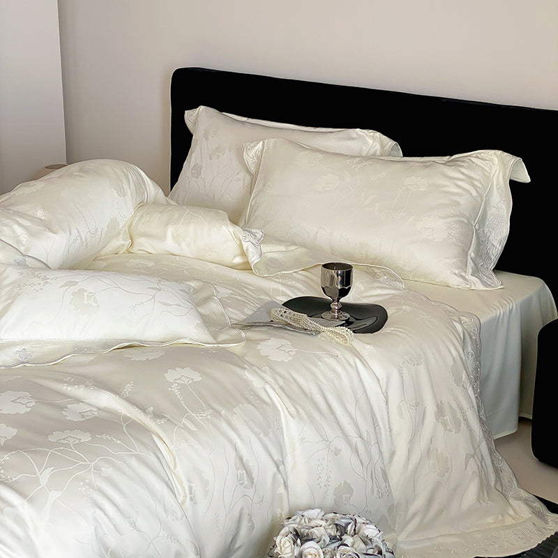 White satin bedding set on a bed with a black headboard.