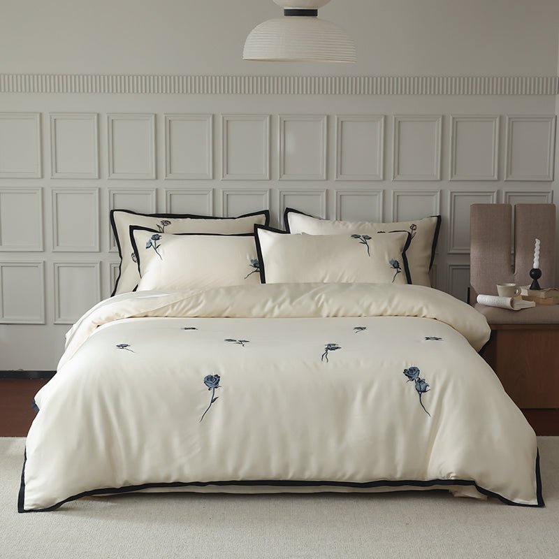 A white duvet cover with black butterfly embroidery, displayed on a bed in a room with a light interior.