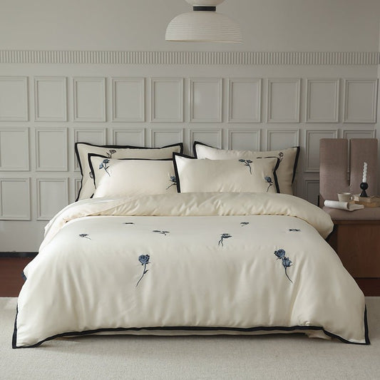 A white duvet cover with black butterfly embroidery, displayed on a bed in a room with a light interior.