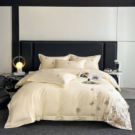 A beige cotton duvet cover set with butterfly embroidery, displayed on a bed in a stylishly decorated bedroom.