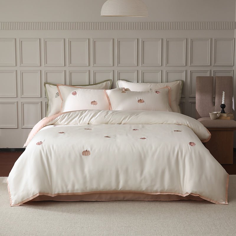 A white duvet cover with embroidered corner details, displayed on a bed in a room with elegant wall paneling.