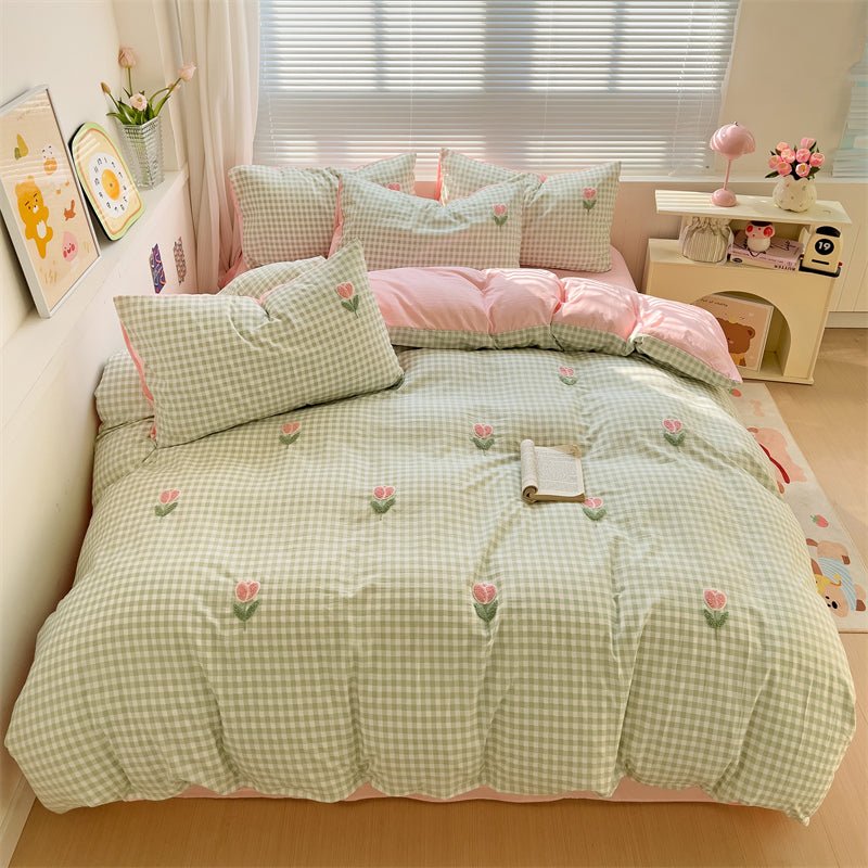 A bedding set with a green checkered pattern and tulip printed designs, displayed in a bedroom setting.