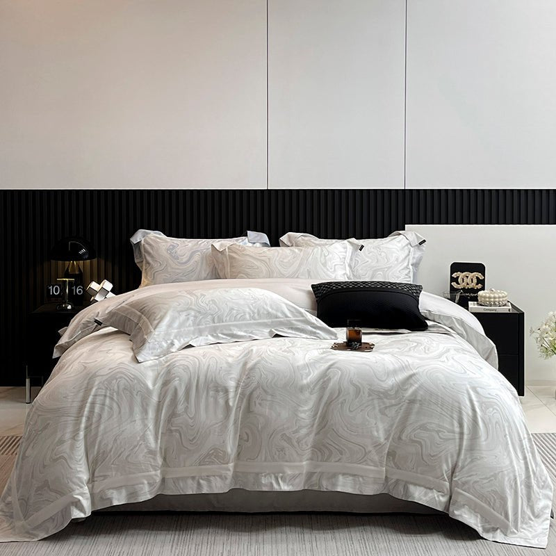 A luxury shadow-weave cotton duvet cover set in white, displayed on a bed with matching pillows and bedsheet, in a room with modern decor.