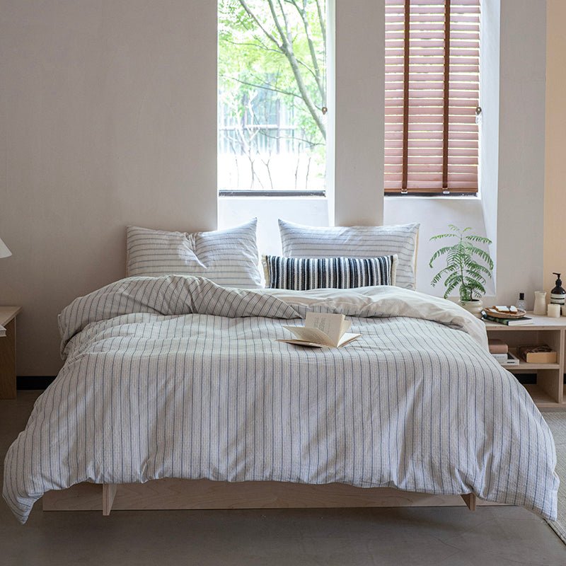 A striped cotton duvet cover set on a bed in a room with window in the background.