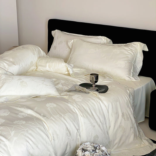 White satin bedding set on a bed with a black headboard.