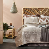 Bedroom with a bed featuring patterned bedding and pillows, wooden headboard, and side table.