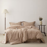 A beige luxury jacquard duvet cover set on a bed, with a lamp and a vase with flowers on the side table.