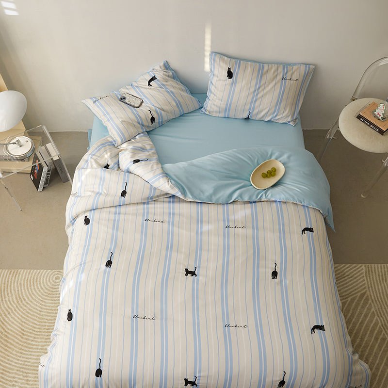A bedding set with white and blue stripes and small animal (whale) patterns, displayed on a bed with pillows and a duvet cover.