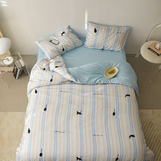 A bedding set with white and blue stripes and small animal (whale) patterns, displayed on a bed with pillows and a duvet cover.
