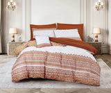 A bedding set with a geometric patchwork design in red and white colors, displayed on a bed with a wooden headboard in a room with ornate wall moldings and decorative lighting.