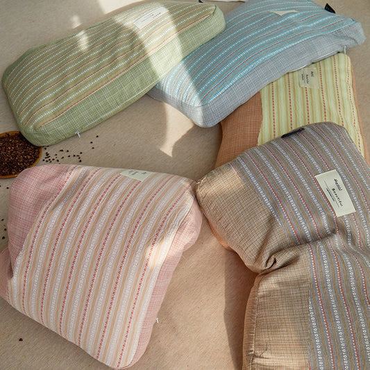 A selection of organic cotton striped buckwheat pillows in various colors including green, blue, pink, beige, and brown.