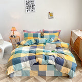 A checkered cotton duvet cover set in yellow, blue, and gray colors displayed on a bed in a room with a side table and a lamp.