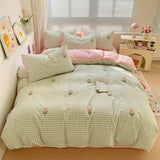 A bedding set with a green checkered pattern and tulip printed designs, displayed in a bedroom setting.