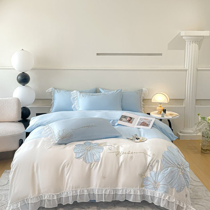 A blue and white duvet cover set on a bed, with decorative pillows, bedazzled with a floral pattern, and placed in a room with a classic decor.