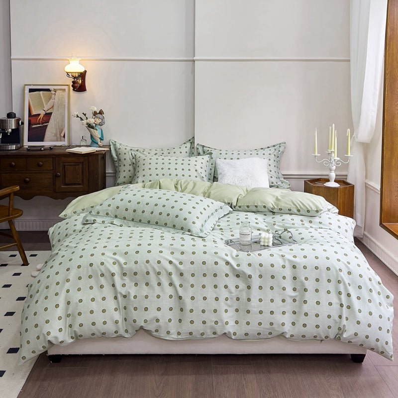 A mint green bedding set with polka dots on a bed, displayed in a room with bedside tables and lamps.