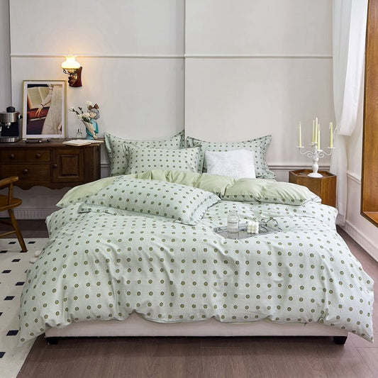 A mint green bedding set with polka dots on a bed, displayed in a room with bedside tables and lamps.