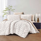 Floral comforter set on a bed in a bedroom with a lamp and plant.