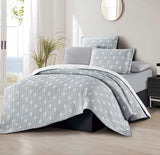 A floral patterned bedding set in gray and white, displayed on a bed with pillows and a comforter.