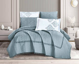 A navy blue quilt with tassel detailing, displayed on a bed in a room with light decor. The quilt set includes matching pillows.