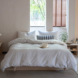 A striped cotton duvet cover set on a bed in a room with window in the background.