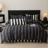 A bedding set with navy and black stripes, displayed on a bed with other pillows and a magazine on the bed's surface.