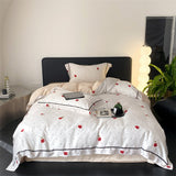 A duvet cover set with a white background featuring red rose and polka dot pattern, displayed on a bed with bedding and pillows.