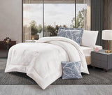 A white leaf-quilted comforter set on a bed, with two pillowcases displayed beside the bed. The bedding appears to have a floral pattern.