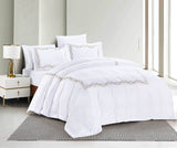 A white bedding set with quilted border design, displayed on a bed with additional details such as a lamp and nightstand in the background.
