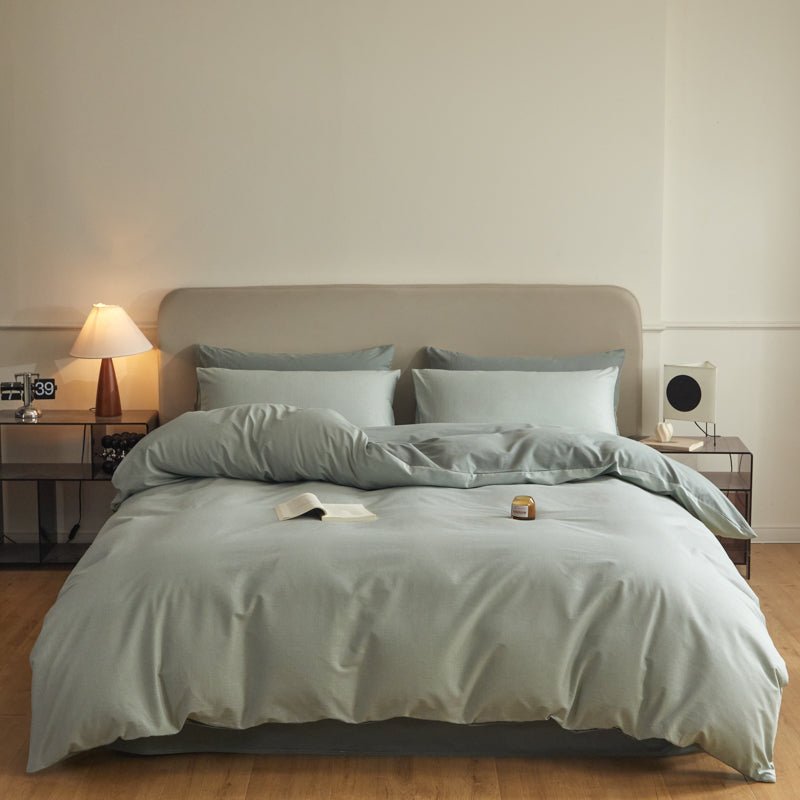 A duvet cover set with green stripes on a bed in a bedroom setting, with a nightstand and a lamp.
